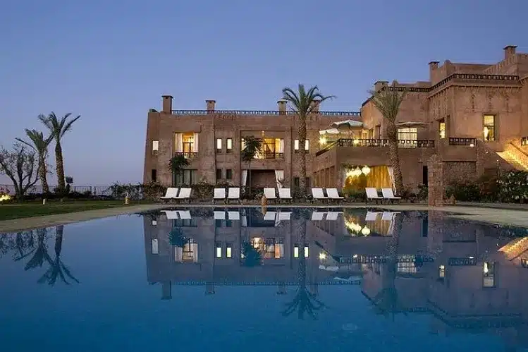 A large house with a pool illuminated at dusk, showcasing a serene atmosphere and vibrant colors in the evening sky. 