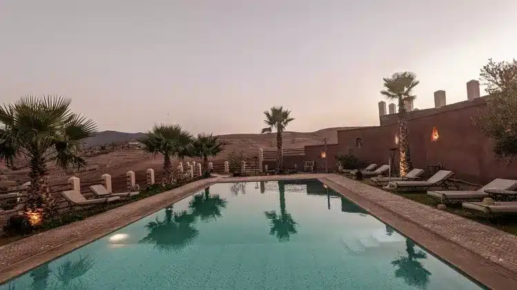 A serene desert pool surrounded by lounge chairs and palm trees, offering a tranquil escape from the arid landscape. 